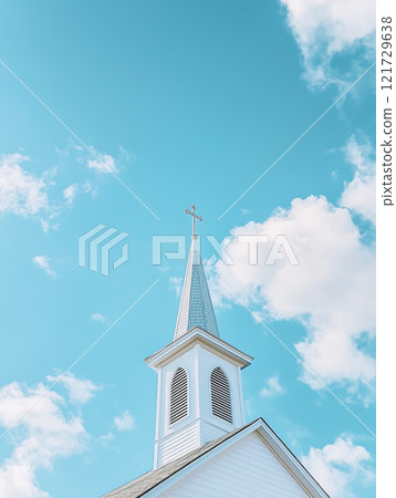 Bright blue sky highlights elegant white church steeple standing tall over serene landscape during a sunny day 121729638