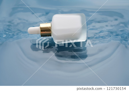 Bottle with white moisturizing serum in water on blue background. Bottle with white moisturizing serum in water on blue background. 121730154