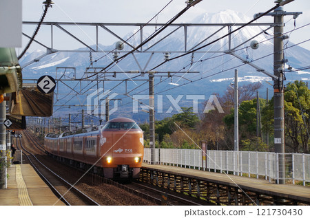 A conventional express train bound for Izumo, 273 series Yakumo No. 7, running on the Sanin Main Line with tourists on board for the New Year's holiday, with the snow-capped Mt. Daisen in the background 121730430