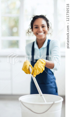 African american young woman cleaning in kitchen with mop and gloves, concept of cleaning service, housework and hygiene African american young woman cleaning in kitchen with mop and gloves, concept of cleaning service, housework and hygiene 121730518
