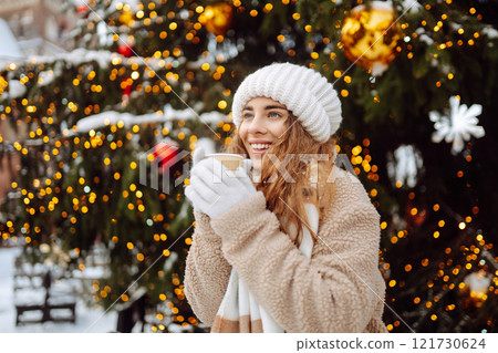 Woman is having fun at a street holiday fair, drinking a hot drink. Winter holidays. Lifestyle. 121730624