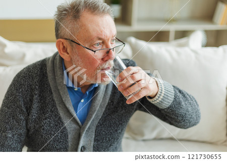 Senior man holding glass drinking fresh water at home. Mature old senior thirsty grandfather takes care of his health. Healthcare water balance. Elderly healthy lifestyle 121730655