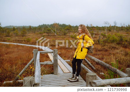 Portrait of happy woman walking along path among marsh nature. Concept of travel. Active lifestyle. 121730998