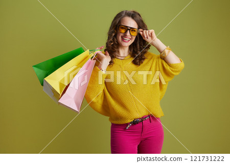 happy trendy female in sweater and sunglasses against green 121731222