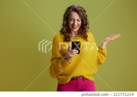happy fit woman using smartphone isolated on green happy fit woman using smartphone isolated on green 121731224