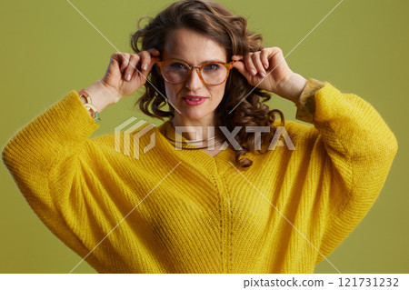 Portrait of trendy female in sweater and glasses against green Portrait of trendy female in sweater and glasses against green 121731232