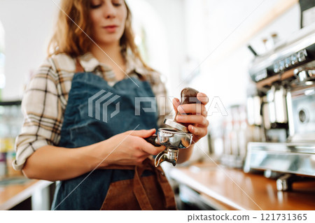 Woman bartender prepares a drink using a coffee machine in a cafe. Takeaway food. 121731365