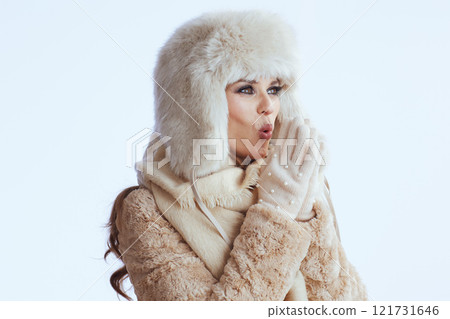 happy stylish woman warming hands with breath on white 121731646