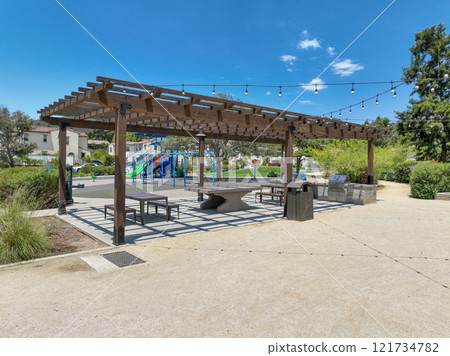 Covered gathering area in city park with green wood picnic tables 121734782
