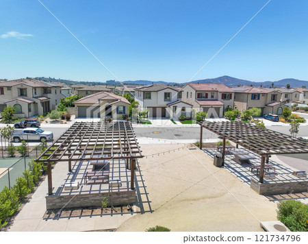 Covered gathering area in city park with green wood picnic tables 121734796