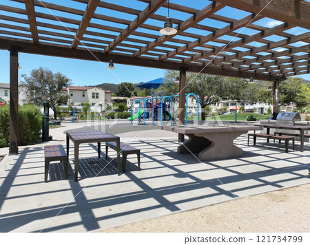 Covered gathering area in city park with green wood picnic tables 121734799