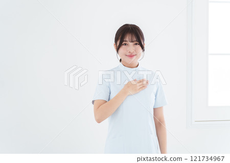 Smiling female nurse putting her hand on her chest 121734967