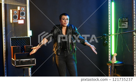 Heavy metal performer acting uncertain and shrugging in doubt, being clueless and uncertain about an answer. Confused doubtful woman artist having no idea about something. Camera B. 121735237