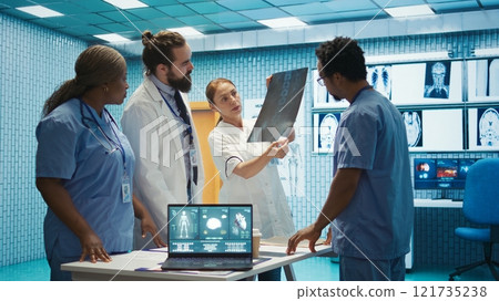 Medic discuss human anatomy scans in a radiology diagnostic meeting at a treatment center, expertise in analyzing x ray results. Doctors examine hospital records and analytics. Camera B. Medic discuss human anatomy scans in a radiology diagnostic meeting at a treatment center, expertise in analyzing x ray results. Doctors examine hospital records and analytics. Camera B. 121735238