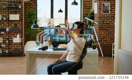 Asian modern editor using virtual reality glasses and mixing video clips, using interactive gadget vr headset to edit and do color grading for a montage. Video editing software. Camera A. Asian modern editor using virtual reality glasses and mixing video clips, using interactive gadget vr headset to edit and do color grading for a montage. Video editing software. Camera A. 121735246