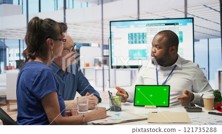 Financial advisor works with a green screen at table with his senior clients, presenting retirement plans and investment options to secure their pension and life savings. Insurance agency. Camera B. Financial advisor works with a green screen at table with his senior clients, presenting retirement plans and investment options to secure their pension and life savings. Insurance agency. Camera B. 121735288