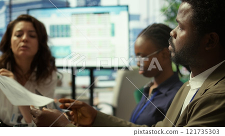 Important business investor studying development progress reports on tablet, examining big data visualization tools during a briefing meeting with executive board members. Management. Camera B. 121735303
