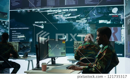 High tech military office with soldiers analyzing real time data, processing intelligence information and coordinating strategic operations to support army field missions effectively. Camera B. High tech military office with soldiers analyzing real time data, processing intelligence information and coordinating strategic operations to support army field missions effectively. Camera B. 121735317