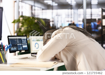 Tired businesswoman at work sleeping on desk while working on laptop to solve business tasks, suffering burnout. Sleepy employee dozing off in office after working overtime to finish project 121735462
