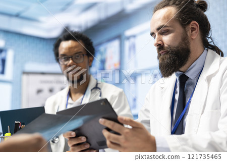 In a meeting, doctors and medical staff focus on x ray scans and test results to put a diagnostic. Their licensed expertise guides the development of treatment plans and disease prevention. In a meeting, doctors and medical staff focus on x ray scans and test results to put a diagnostic. Their licensed expertise guides the development of treatment plans and disease prevention. 121735465