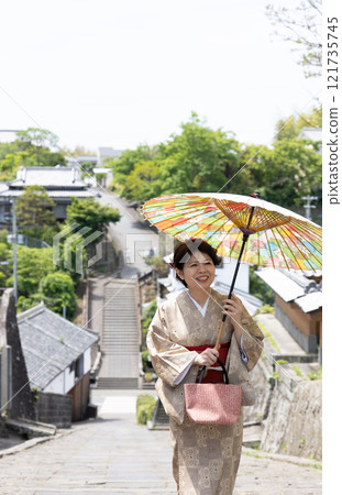 在大分縣杵築市，一名身穿日式服飾的女子站在一家醋店的斜坡上。 121735745