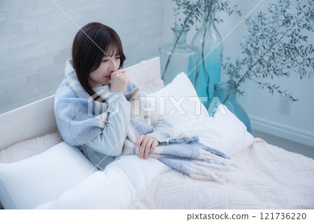 A woman coughing in bed with a cold 121736220