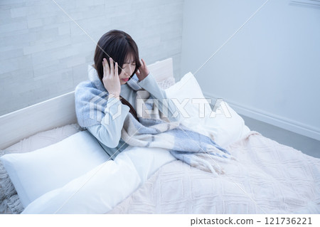A woman who can't get out of bed because of stress and holds her head A woman who can't get out of bed because of stress and holds her head 121736221