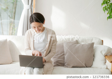 A woman using a computer in the living room A woman using a computer in the living room 121736336