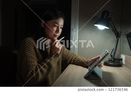 woman thinking while using tablet at night woman thinking while using tablet at night 121736596