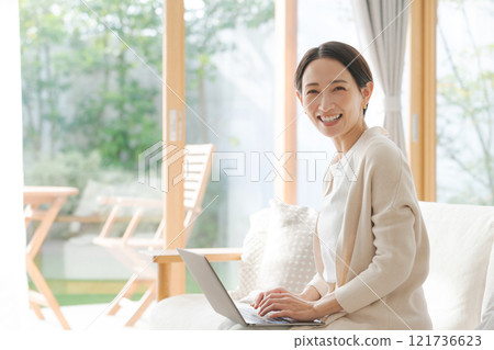一位女士在沙發上用電腦工作 一位女士在沙發上用電腦工作 121736623