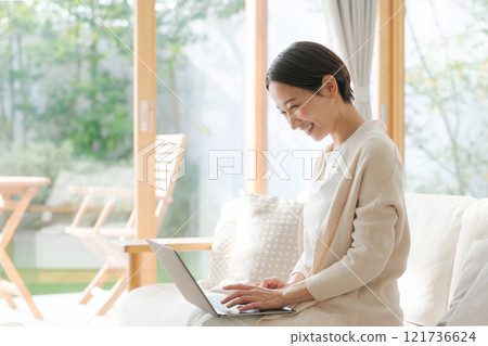 Woman working on a computer on the sofa 121736624