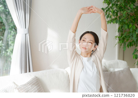 A woman sitting by the window and stretching 121736820