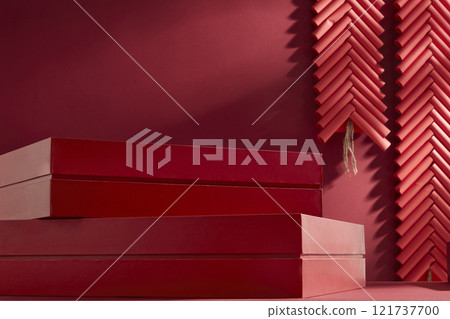A low-angle view shows two rectangular boxes stacked, creating a blank space for presentation products, adorned with two string firecrackers on a crimson backdrop. Chinese New Year theme. 121737700