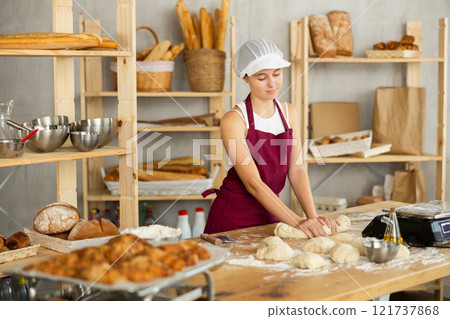 Teenage girl rolls out dough in bakery 121737868