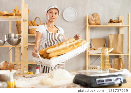 Woman baker with baguettes 121737929