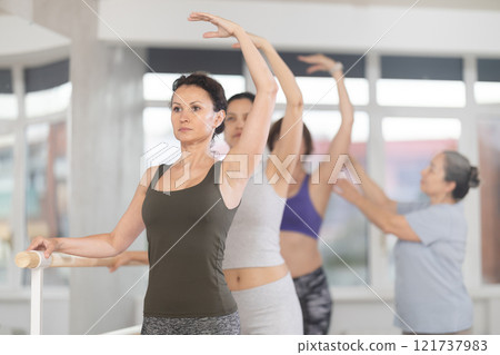 Elderly woman teacher correcting female dancers Elderly woman teacher correcting female dancers 121737983