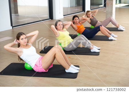 Women practicing pilates with balls at group class in yoga studio Women practicing pilates with balls at group class in yoga studio 121738002