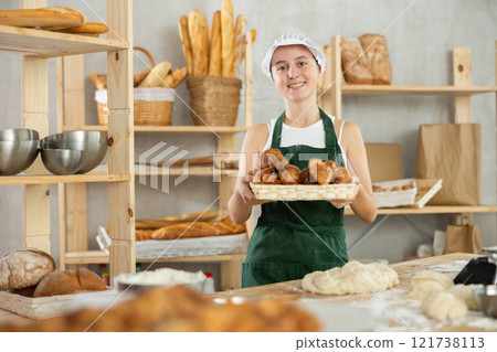 Teen girl holding croissants in square wicker basket 121738113