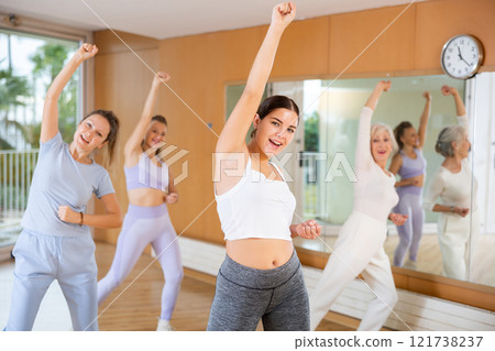 Active young woman practicing aerobic dance in training hall 121738237