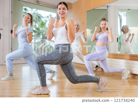 Active young woman practicing aerobic dance in training hall 121738240