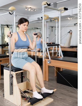 Young asian girl exercising on wunda chair in pilates studio 121738250