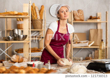 Woman works in bakery as baker, kneads dough, works with flour. Woman works in bakery as baker, kneads dough, works with flour. 121738313