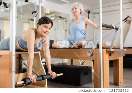 Young positive woman doing Pilates on special equipment in gym 121738412