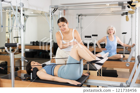 Asian girl doing pilates on reformer with trainer in fitness studio 121738456