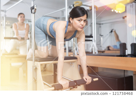 Young asian woman practicing pilates on wunda chair Young asian woman practicing pilates on wunda chair 121738468