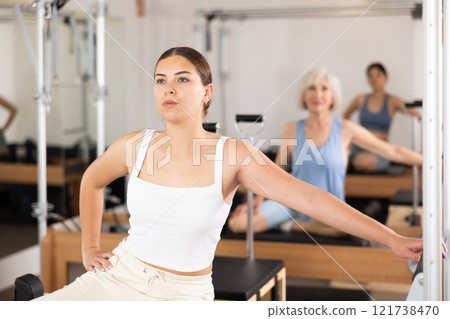Young girl doing exercises on reformer in pilates studio Young girl doing exercises on reformer in pilates studio 121738470