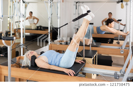 Sporty aged woman doing exercises on Pilates reformer 121738475