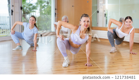 Dynamic women doing stretching in training hall 121738481