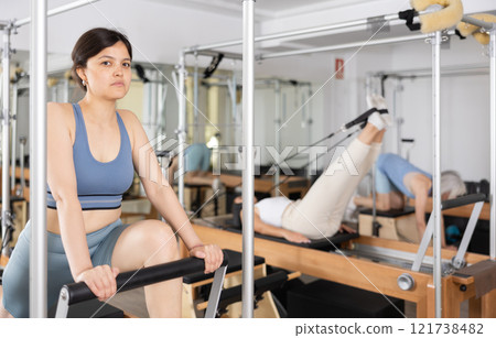 Young asian woman practicing exercises on Pilates reformer 121738482
