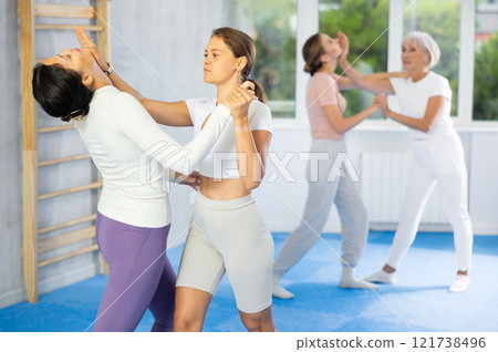 Young woman practicing palm strike to chin during sparring at self-defense course 121738496